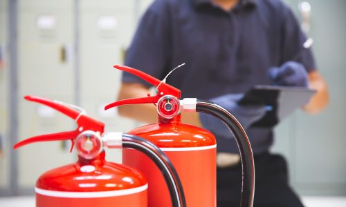Fire extinguisher has hand engineer inspection checking pressure gauges to prepare fire equipment for protection and prevent emergency and safety rescue and alarm system training concept.