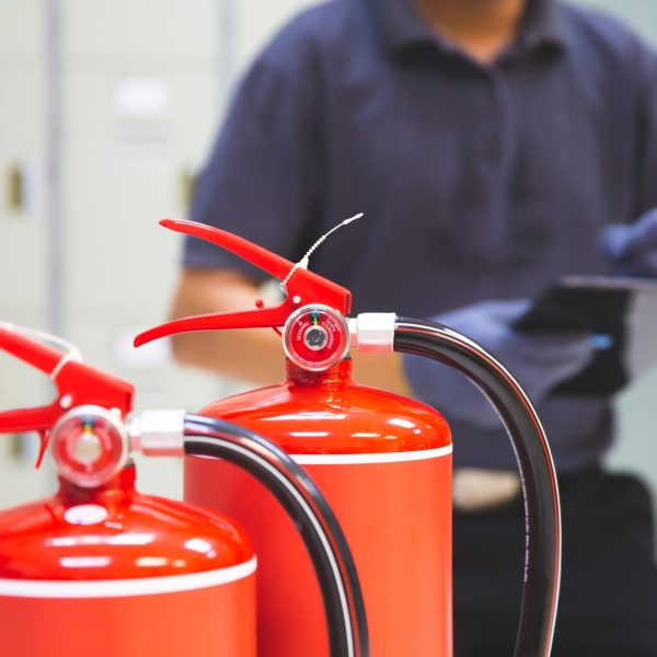 Fire extinguisher has hand engineer inspection checking pressure gauges to prepare fire equipment for protection and prevent emergency and safety rescue and alarm system training concept.