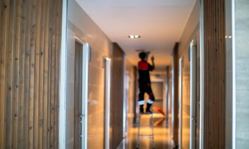 Blurry picture of Technician is replacing or repair a smoke detector in an office building or condominium.  Technician is checking a fire alarm system at smoke detector. Building support.