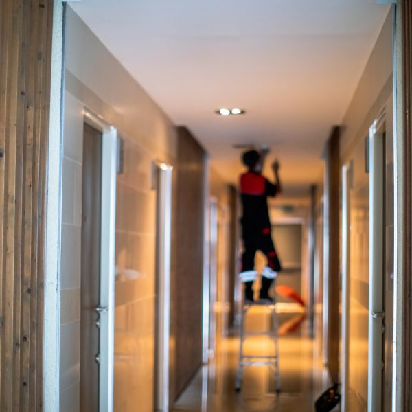 Blurry picture of Technician is replacing or repair a smoke detector in an office building or condominium.  Technician is checking a fire alarm system at smoke detector. Building support.