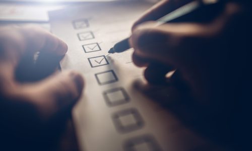 Close-up of businessmans hands filling a checklist