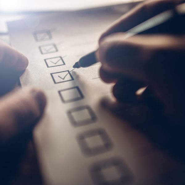 Close-up of businessmans hands filling a checklist